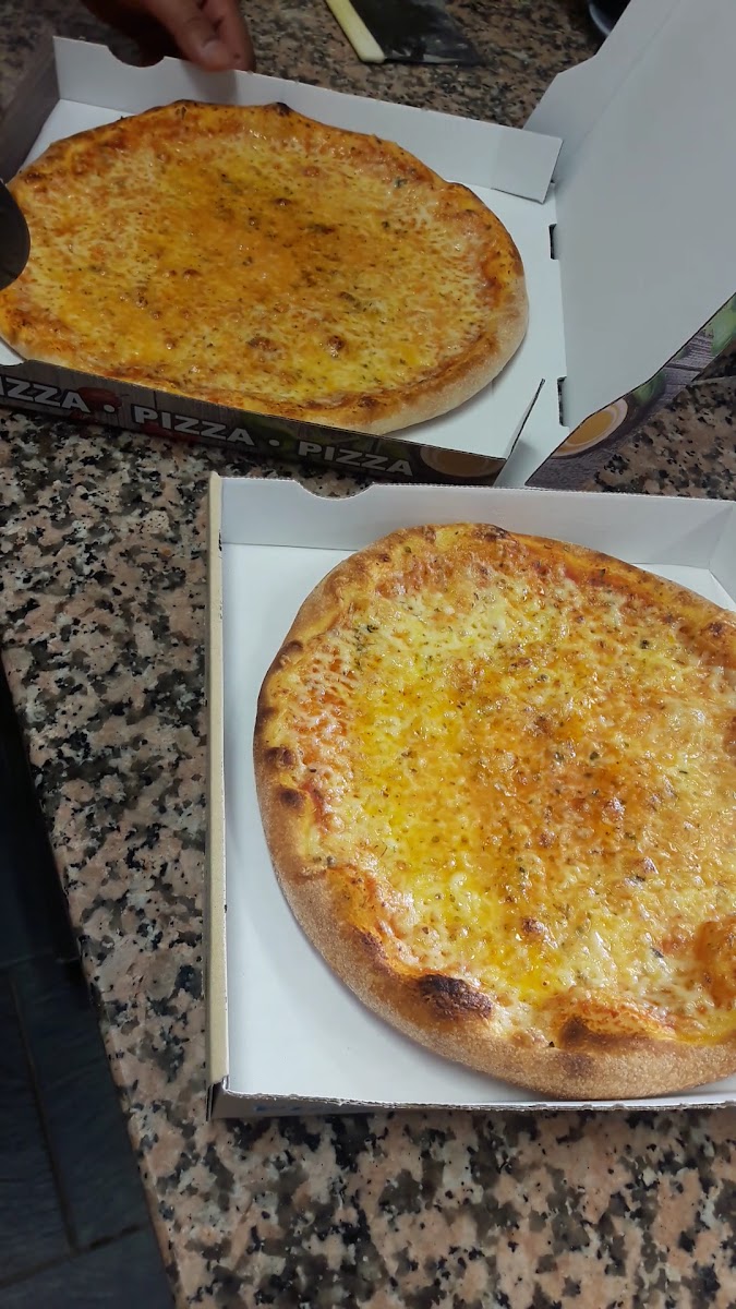 Mitarbeiter des Istanbul Grill schneidet frisch gebackene Pizza